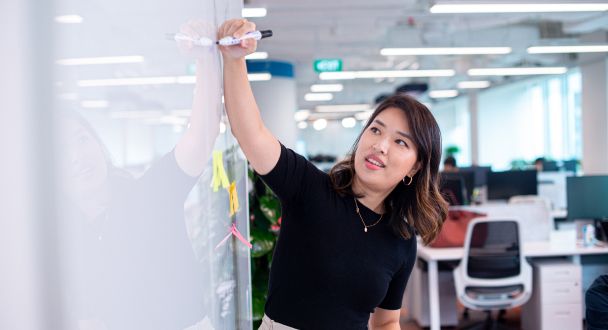 A young Asian female ByteDance PhD Intern writes on a whiteboard.