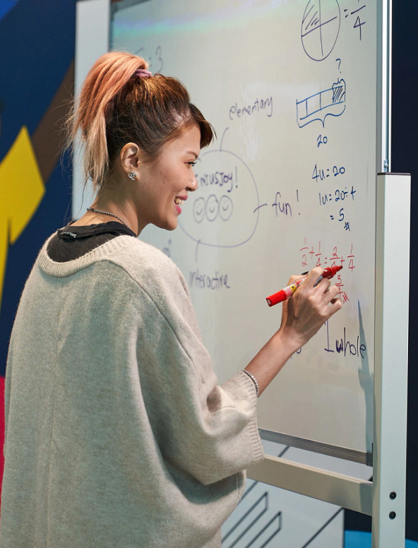 A young Asian female ByteDance employee writes on a whiteboard